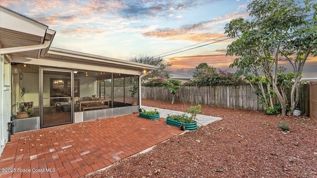 patio terrace at dusk featuring a sunroom