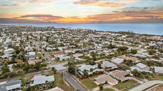 aerial view at dusk featuring a water view