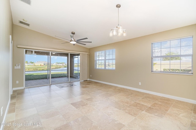 empty room with ceiling fan with notable chandelier, vaulted ceiling, and a healthy amount of sunlight