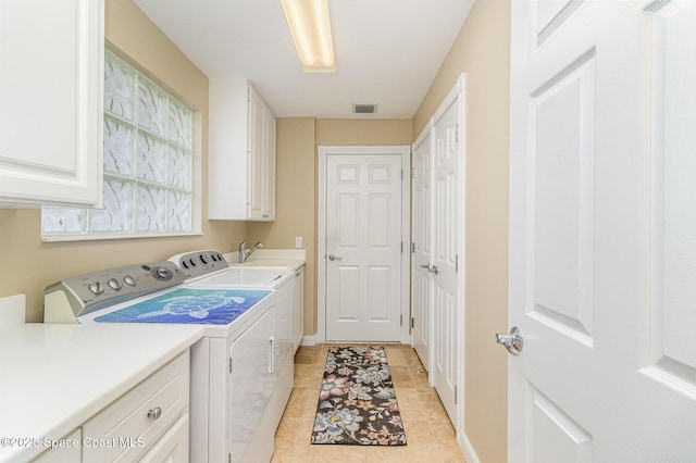 clothes washing area with washer and dryer, cabinets, and sink