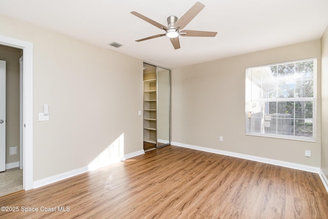 unfurnished bedroom featuring light wood-type flooring, ceiling fan, and a closet