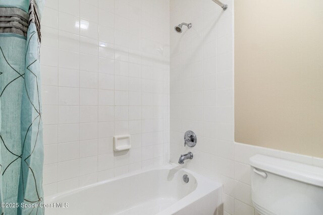 bathroom featuring tile walls, shower / bath combo with shower curtain, and toilet