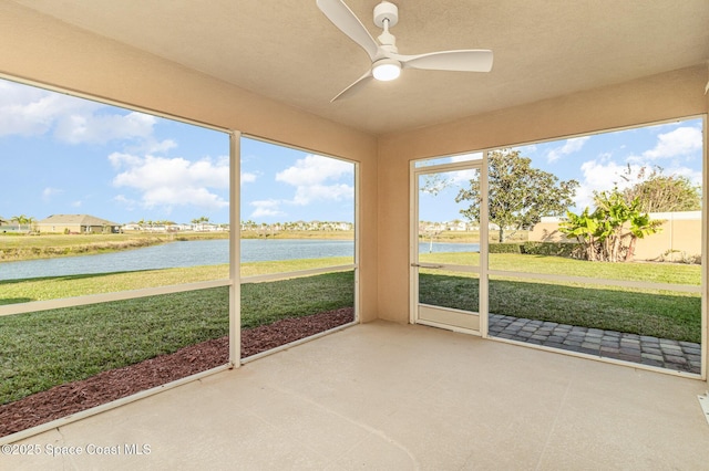 unfurnished sunroom with ceiling fan, a water view, and plenty of natural light