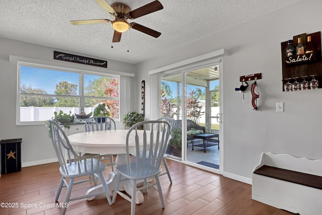 dining space featuring ceiling fan, plenty of natural light, a textured ceiling, and dark hardwood / wood-style flooring