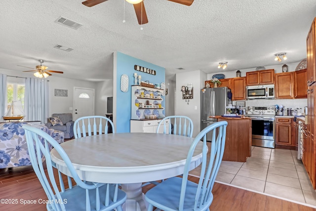 dining room with ceiling fan, a textured ceiling, and light hardwood / wood-style floors