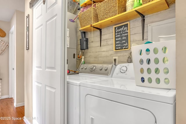 laundry area featuring washer and clothes dryer, wood-type flooring, and wooden walls