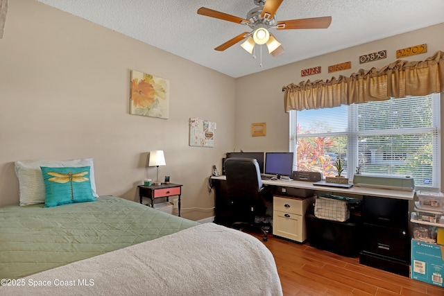 bedroom with ceiling fan, a textured ceiling, and light hardwood / wood-style flooring