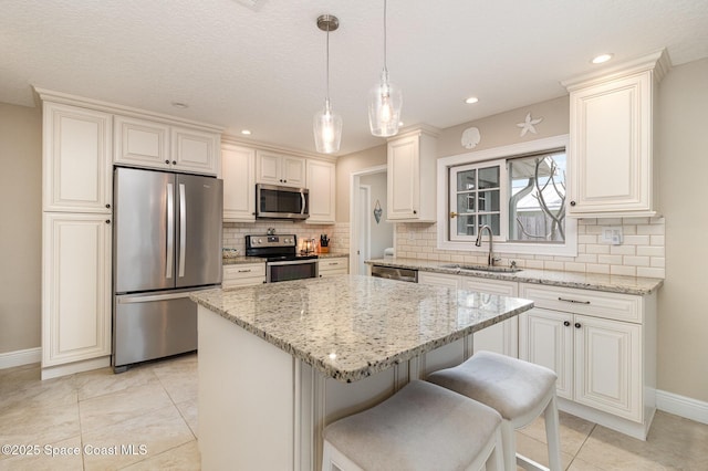 kitchen featuring decorative light fixtures, a center island, sink, appliances with stainless steel finishes, and light stone counters