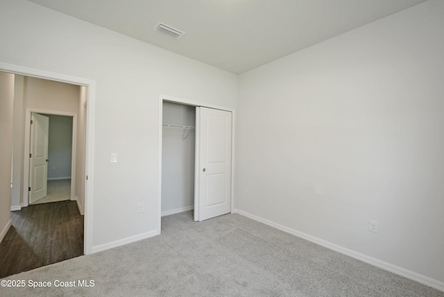 unfurnished bedroom featuring a closet and light colored carpet