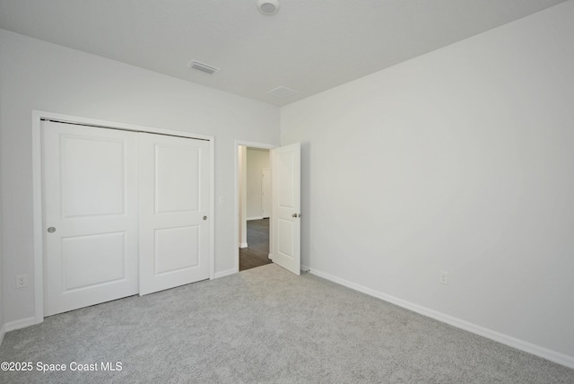 unfurnished bedroom with light colored carpet and a closet