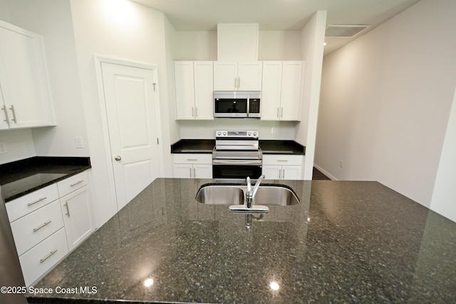 kitchen with dark stone countertops, white cabinetry, sink, and appliances with stainless steel finishes