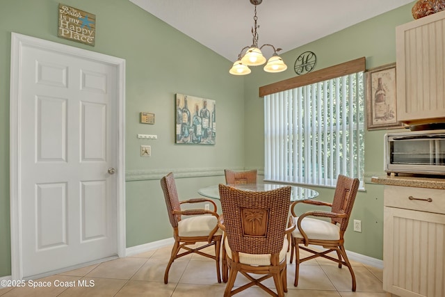 dining space featuring a notable chandelier, light tile patterned flooring, and vaulted ceiling