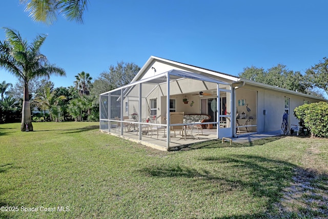 rear view of house featuring a patio, ceiling fan, a lanai, and a lawn