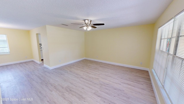 spare room with a textured ceiling, light wood-type flooring, and ceiling fan