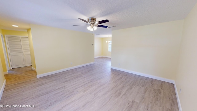 unfurnished room featuring light hardwood / wood-style flooring, ceiling fan with notable chandelier, and a textured ceiling