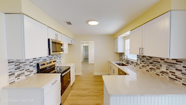 kitchen with backsplash, sink, white cabinets, and stainless steel appliances