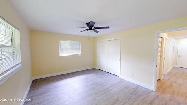 unfurnished bedroom with multiple windows, a closet, light hardwood / wood-style flooring, and ceiling fan