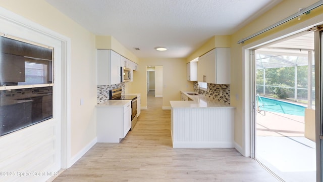 kitchen with sink, tasteful backsplash, light hardwood / wood-style floors, white cabinets, and appliances with stainless steel finishes