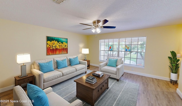 living room with a textured ceiling, light hardwood / wood-style flooring, and ceiling fan