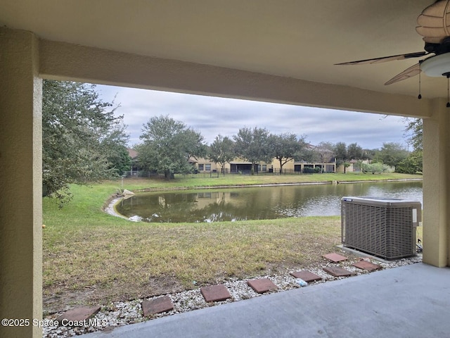 view of yard featuring central AC unit, ceiling fan, and a water view