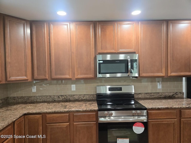 kitchen with tasteful backsplash, stone counters, and stainless steel appliances