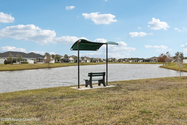 view of dock with a lawn and a water view