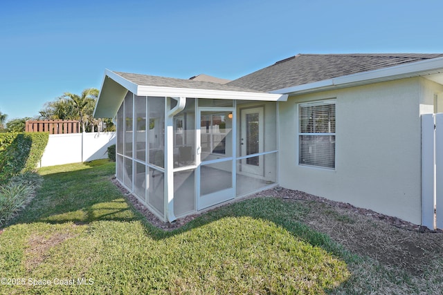 rear view of house featuring a sunroom and a lawn