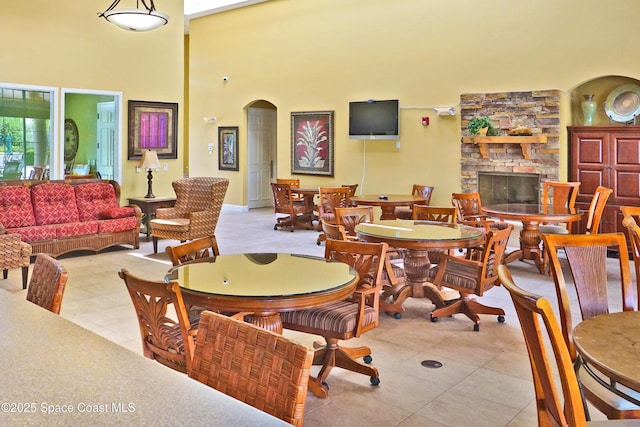 dining area with a towering ceiling and a fireplace