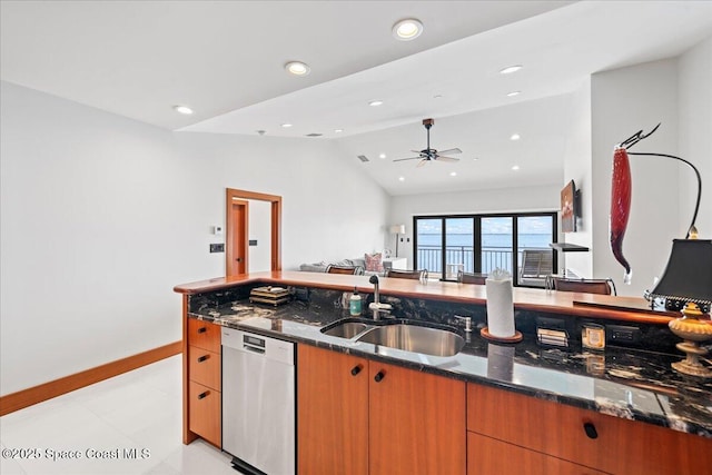 kitchen with dark stone countertops, sink, vaulted ceiling, light tile patterned floors, and stainless steel dishwasher