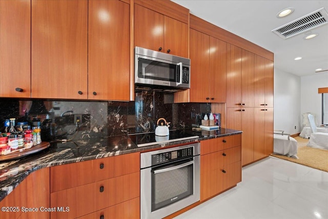 kitchen with light tile patterned flooring, tasteful backsplash, dark stone countertops, and stainless steel appliances