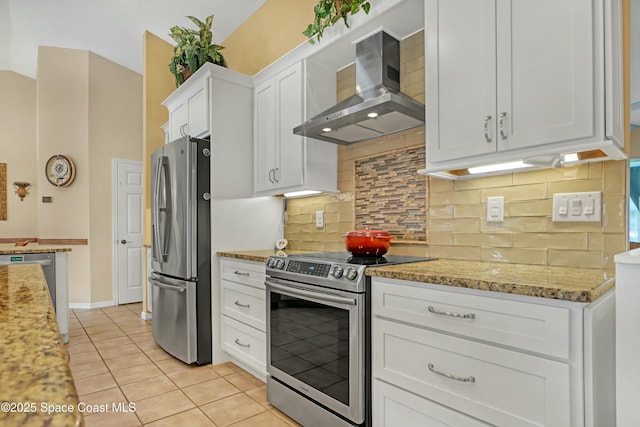 kitchen featuring stainless steel appliances, white cabinetry, light tile patterned floors, decorative backsplash, and wall chimney range hood