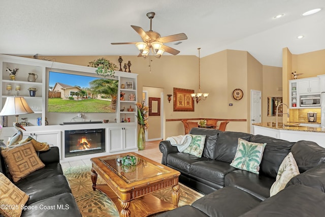 living room with lofted ceiling, sink, light tile patterned floors, and ceiling fan with notable chandelier