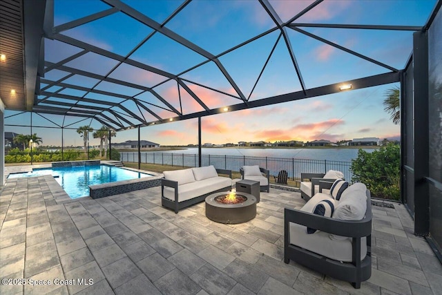 patio terrace at dusk with a water view, a fenced in pool, glass enclosure, and an outdoor living space with a fire pit