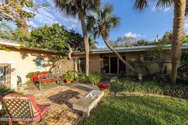 back of property with brick siding, a patio area, and stucco siding