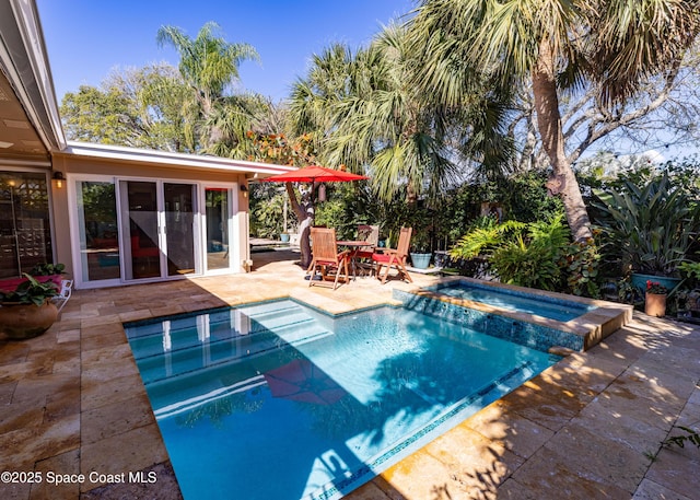 view of pool with a patio area and a pool with connected hot tub