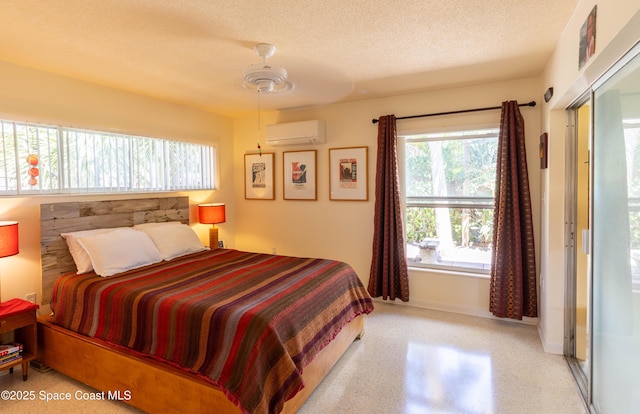 bedroom featuring a textured ceiling, light speckled floor, a ceiling fan, baseboards, and a wall mounted AC