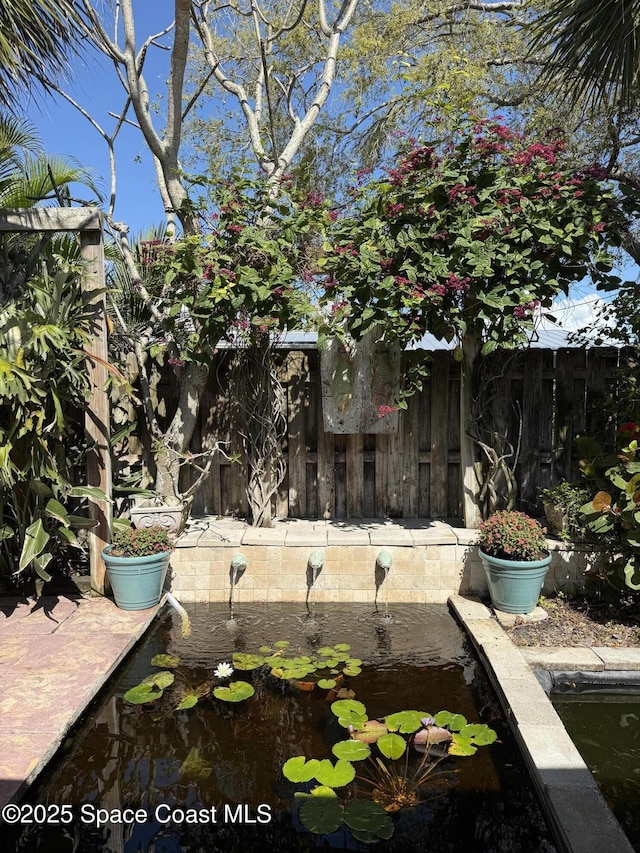 view of yard with fence and a small pond