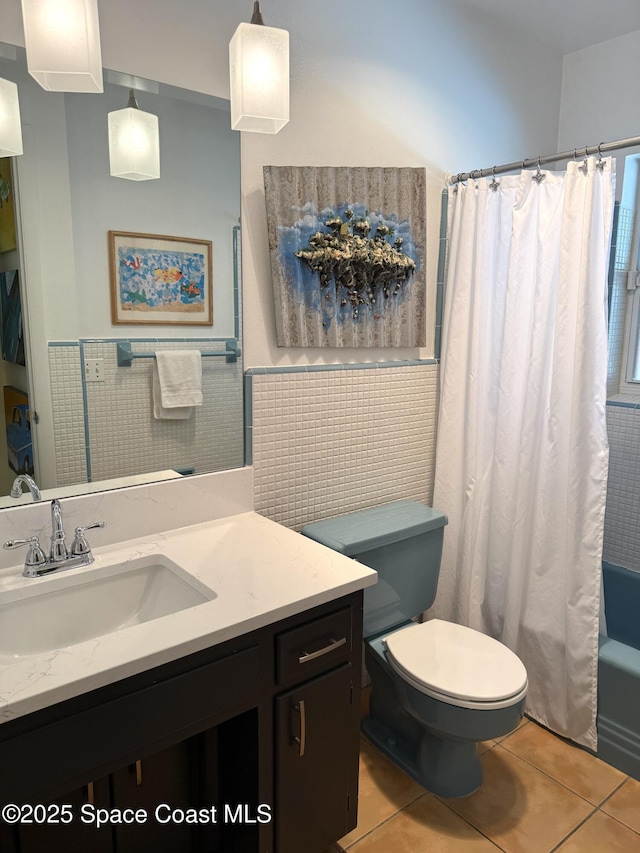 full bathroom with toilet, tile walls, vanity, wainscoting, and tile patterned floors