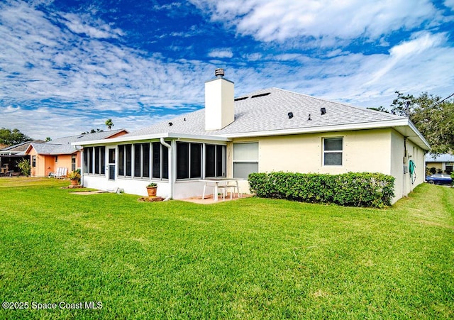 rear view of property with a lawn, a patio area, and a sunroom