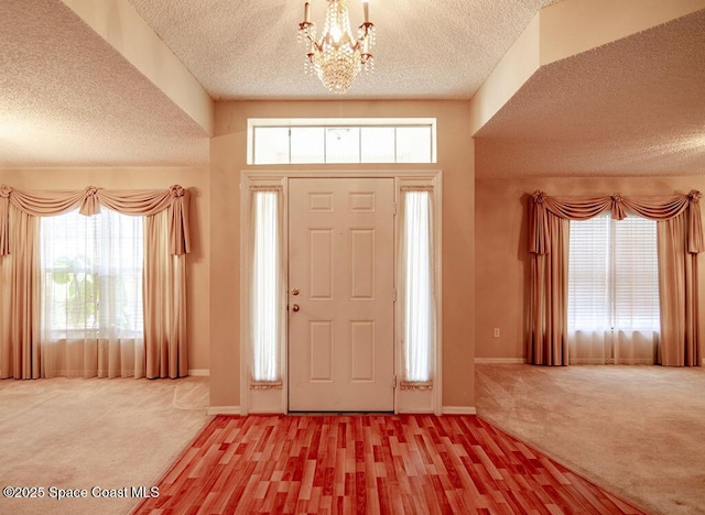 entrance foyer featuring carpet floors, a chandelier, and a textured ceiling