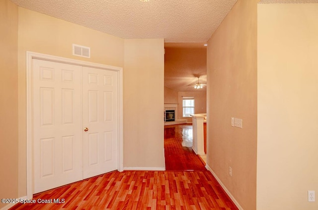 corridor with a textured ceiling and hardwood / wood-style flooring