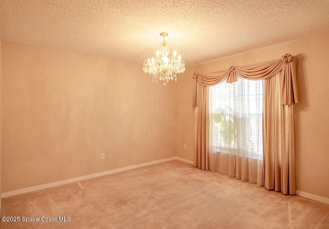 carpeted empty room featuring a textured ceiling and a chandelier