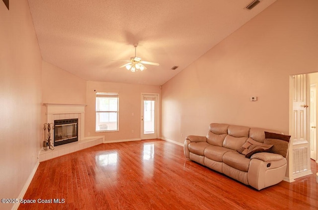 unfurnished living room featuring a textured ceiling, a fireplace, ceiling fan, hardwood / wood-style flooring, and high vaulted ceiling