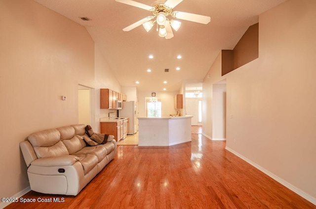 unfurnished living room featuring high vaulted ceiling, ceiling fan, and light hardwood / wood-style floors