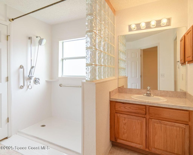 bathroom with vanity, a textured ceiling, and walk in shower