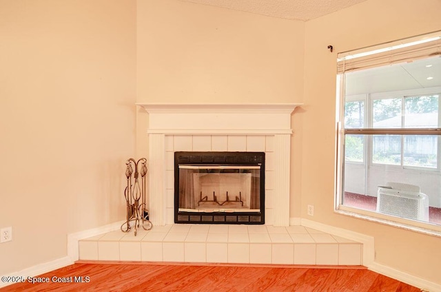 interior details with hardwood / wood-style flooring and a tiled fireplace