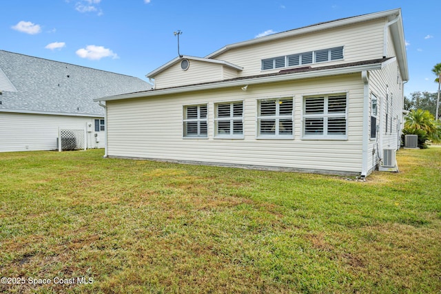 back of house with central AC unit and a lawn