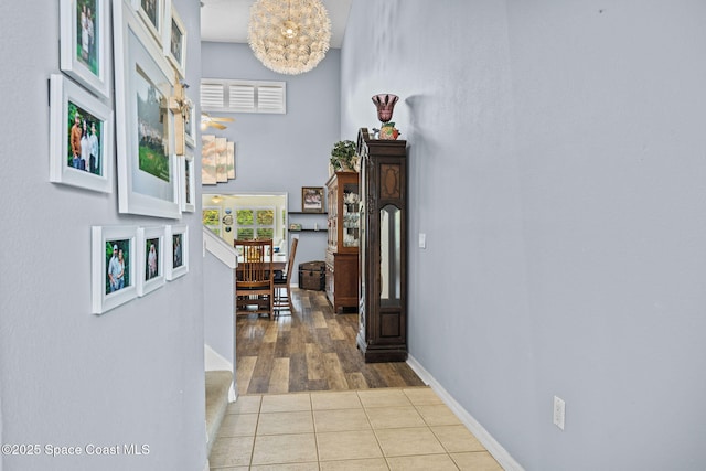 corridor featuring an inviting chandelier and light tile patterned floors