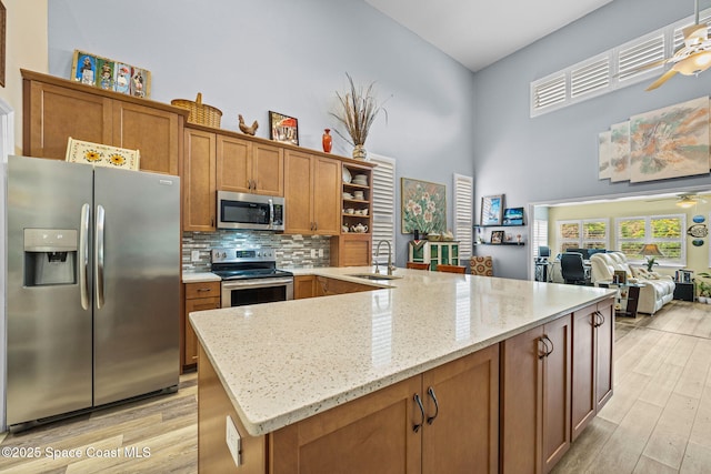 kitchen with ceiling fan, sink, stainless steel appliances, and light stone countertops