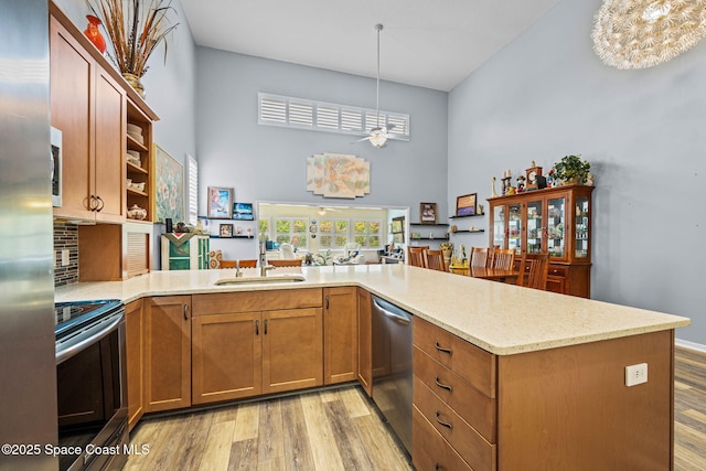 kitchen with decorative light fixtures, sink, appliances with stainless steel finishes, and kitchen peninsula